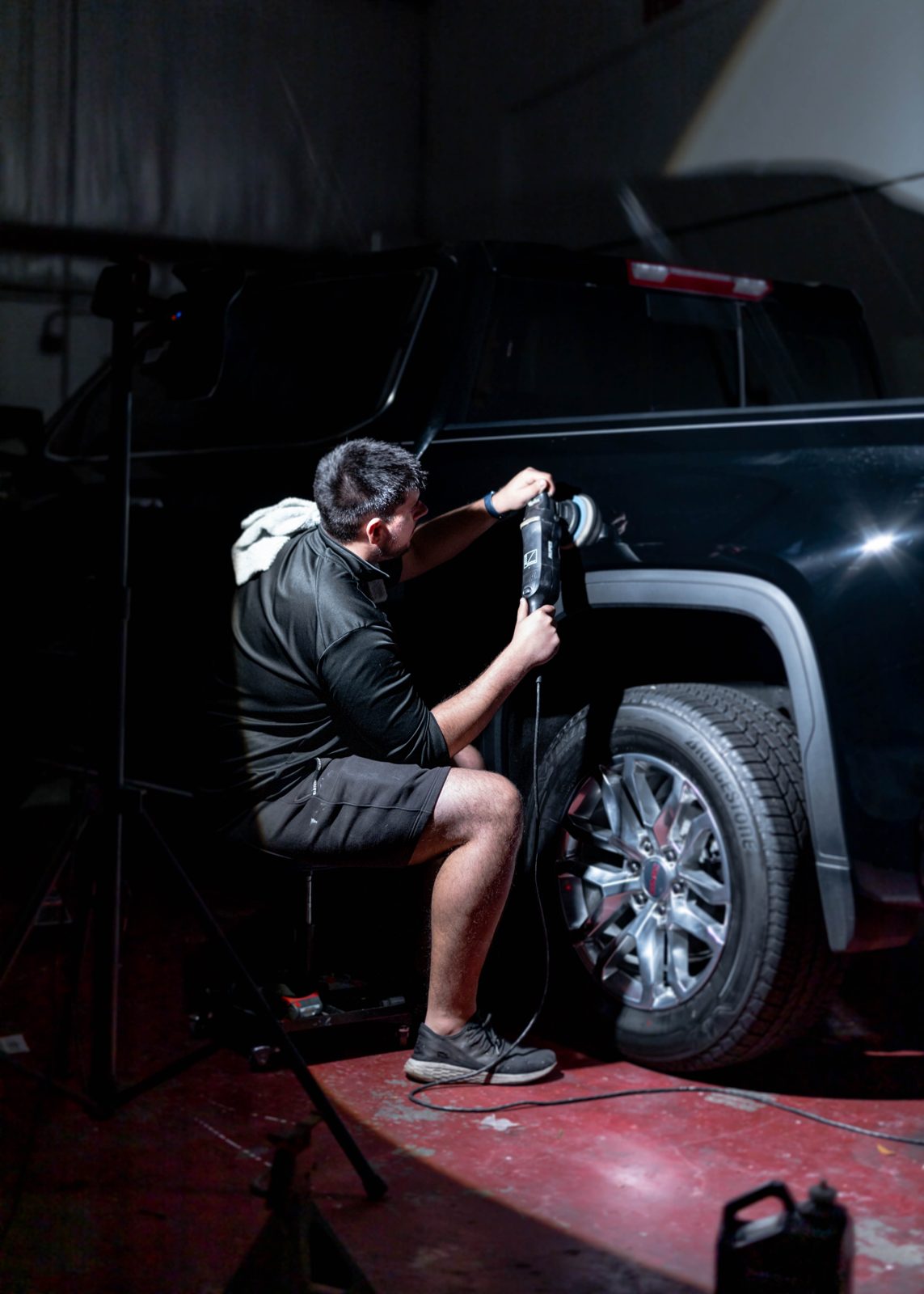 Obsidian detailer buffing a black truck for paint correction at a Baltimore home