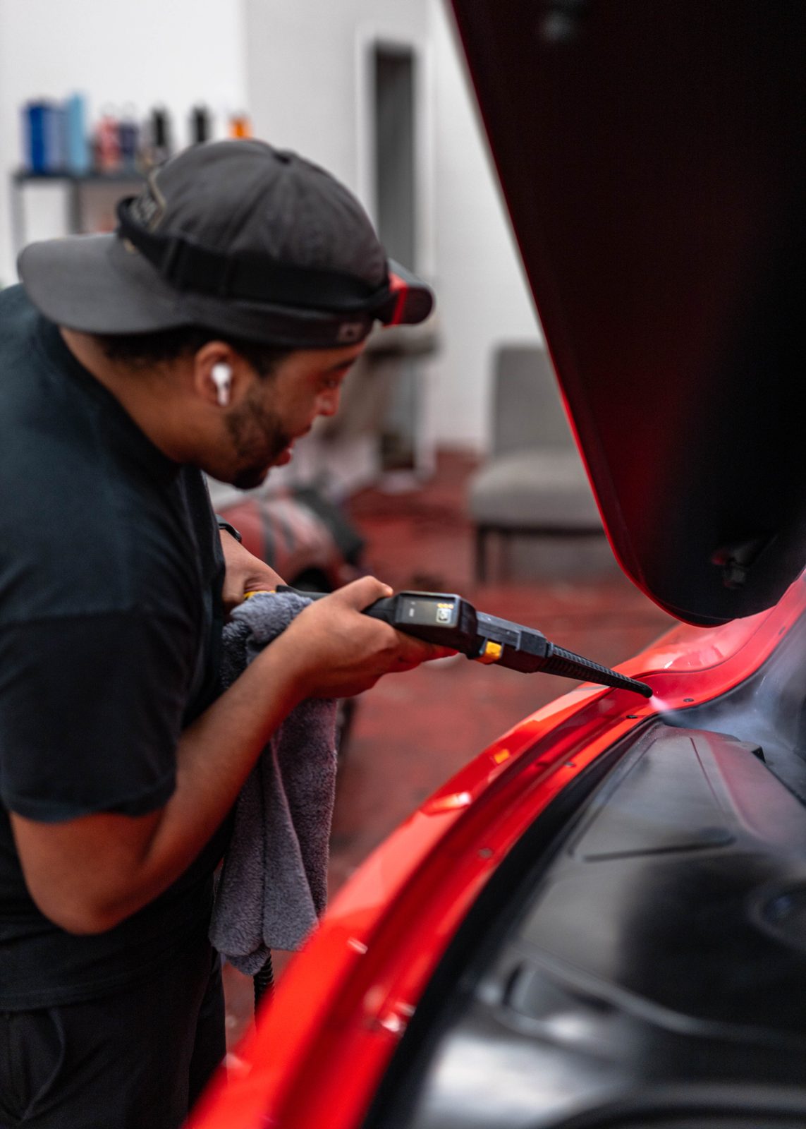 Obsidian detailer machine-polishing a red supercar at a Baltimore location